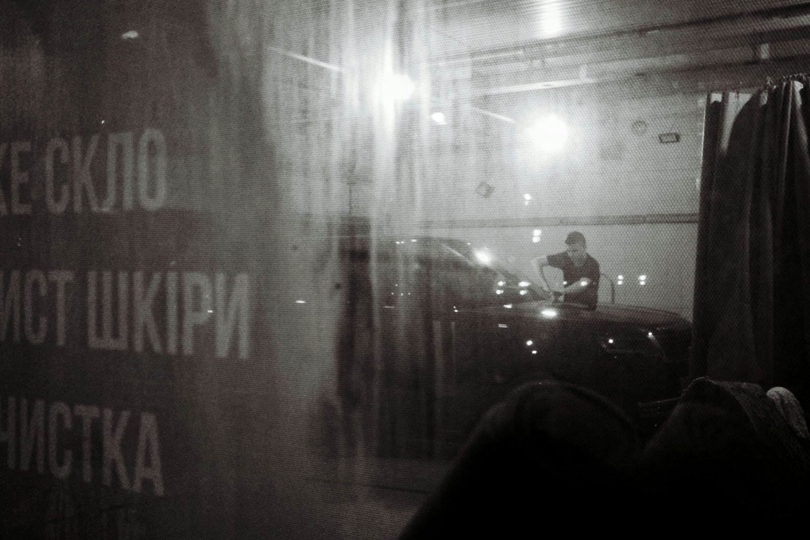 Man washing car in a dimly lit garage.