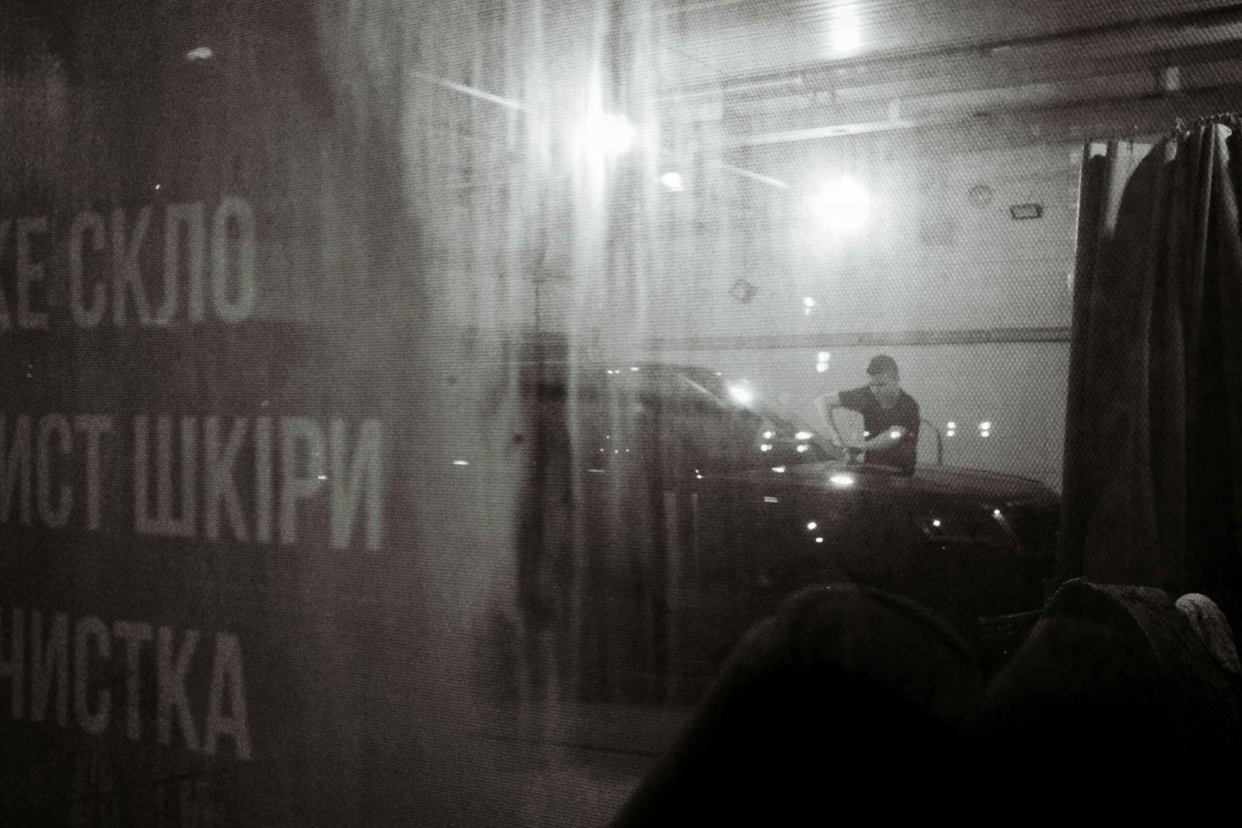 Man washing car in a dimly lit garage.