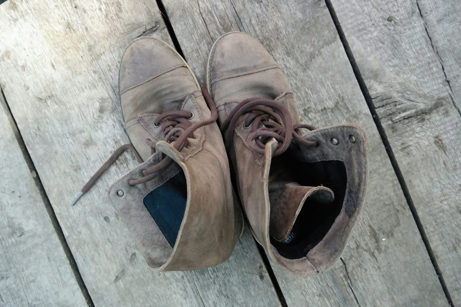 a pair of brown shoes sitting on top of a wooden deck