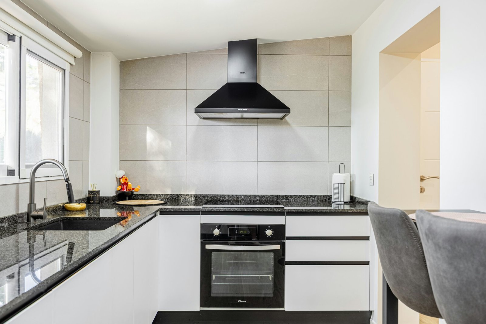 Modern kitchen with black countertops and stainless steel appliances.