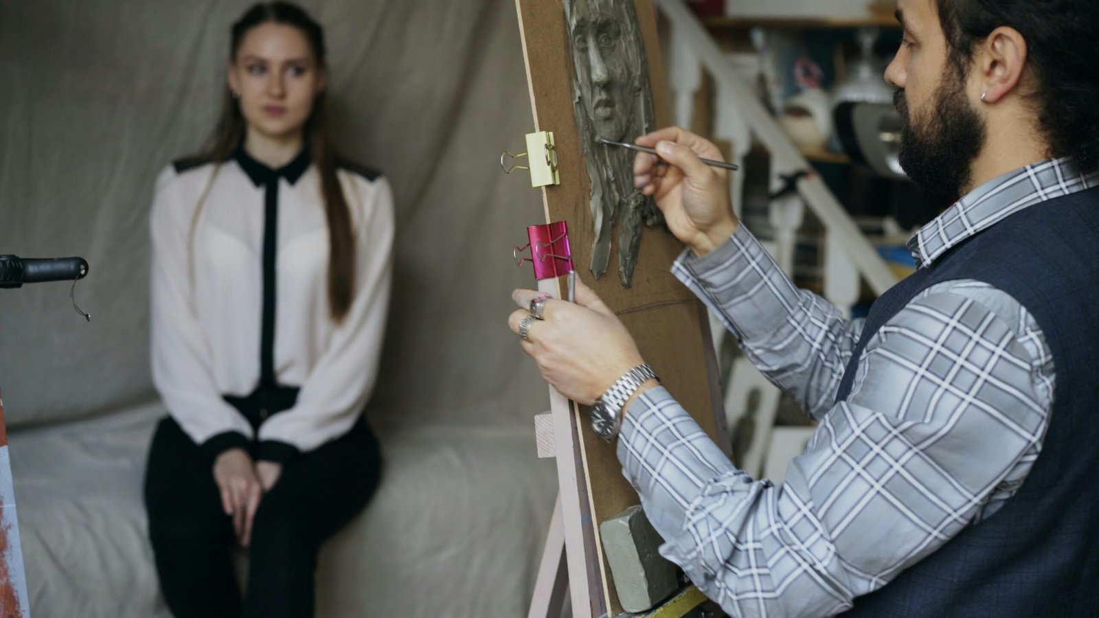 Artist painting a portrait of a seated woman.