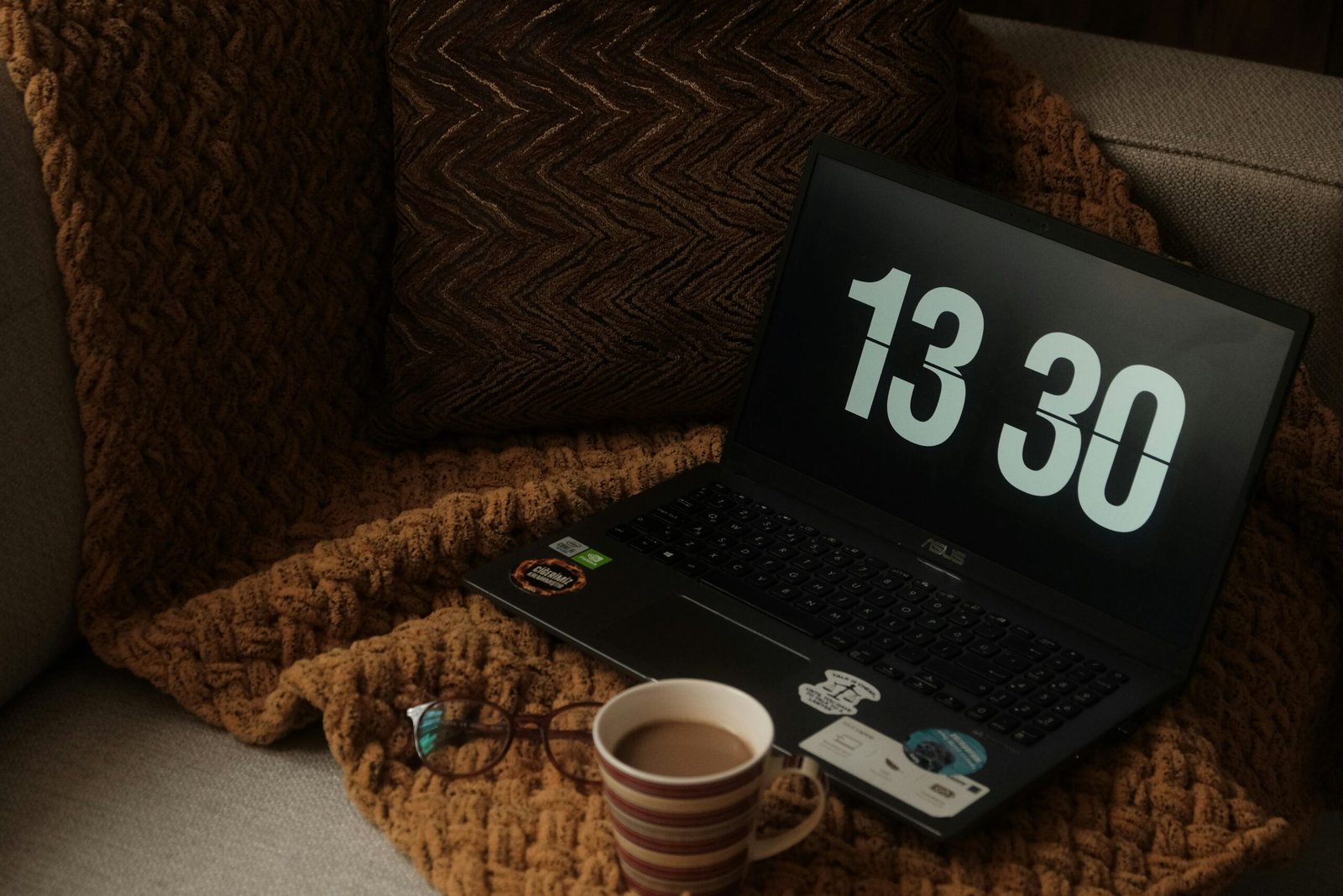 a laptop computer sitting on top of a couch next to a cup of coffee