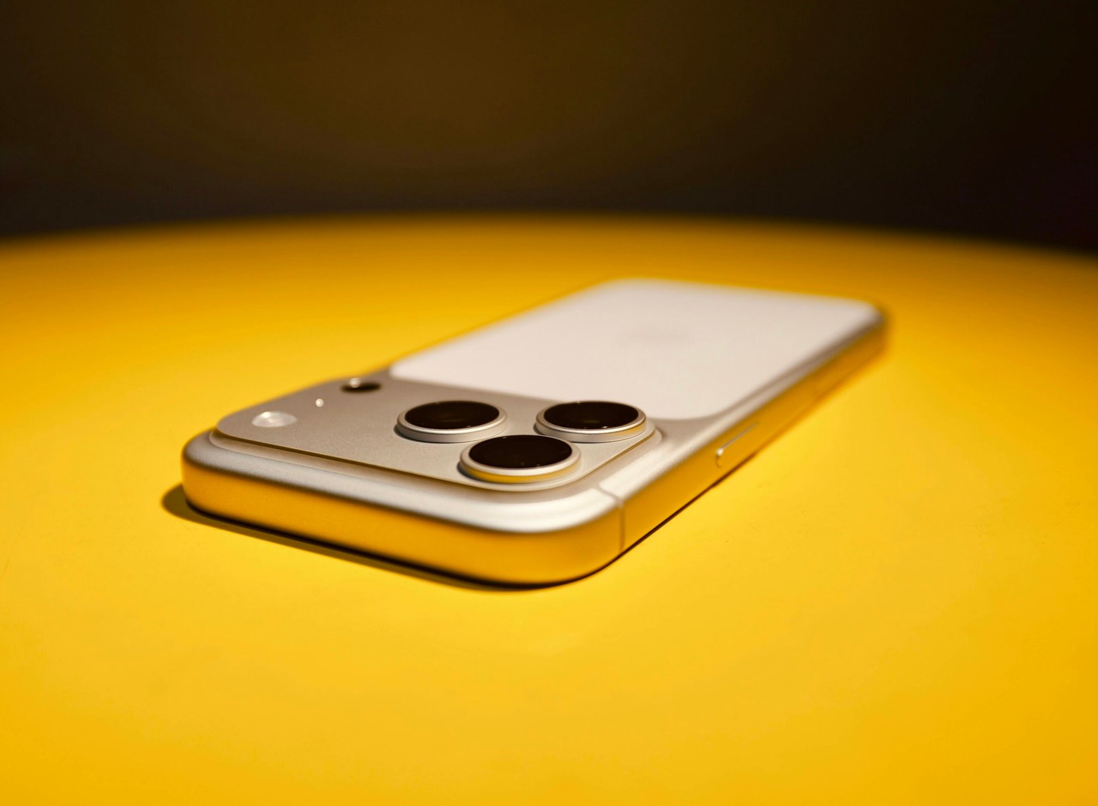 Smartphone with three cameras on yellow surface