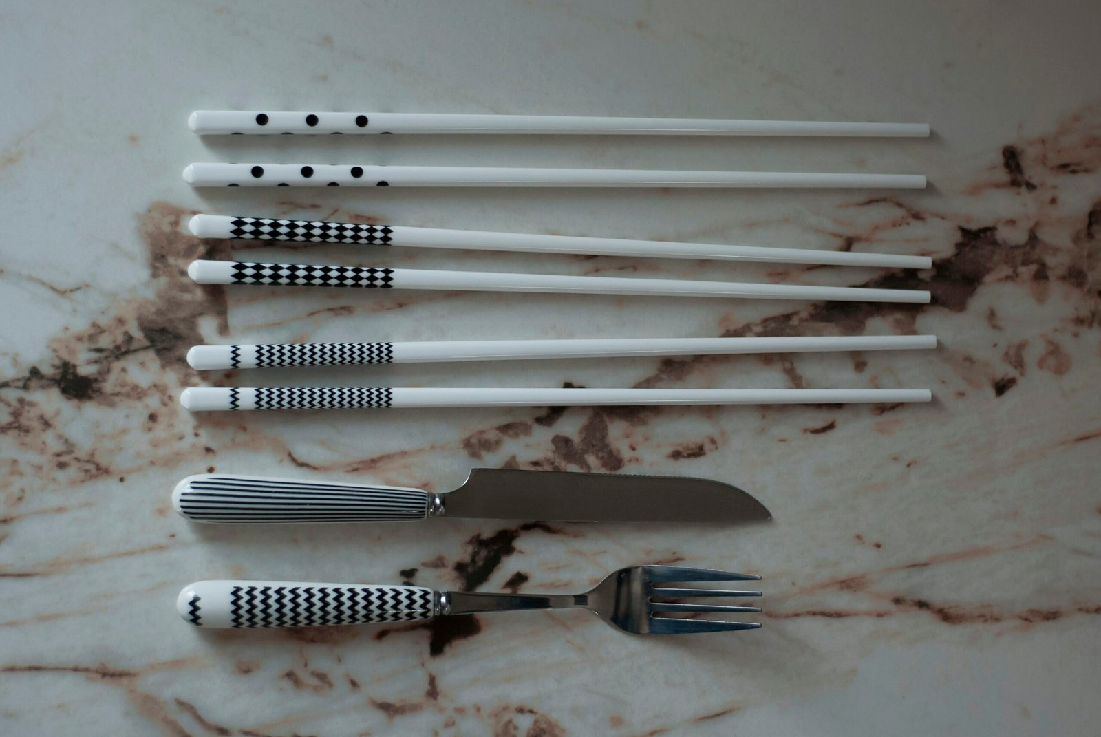 A set of five forks and a knife on a marble counter