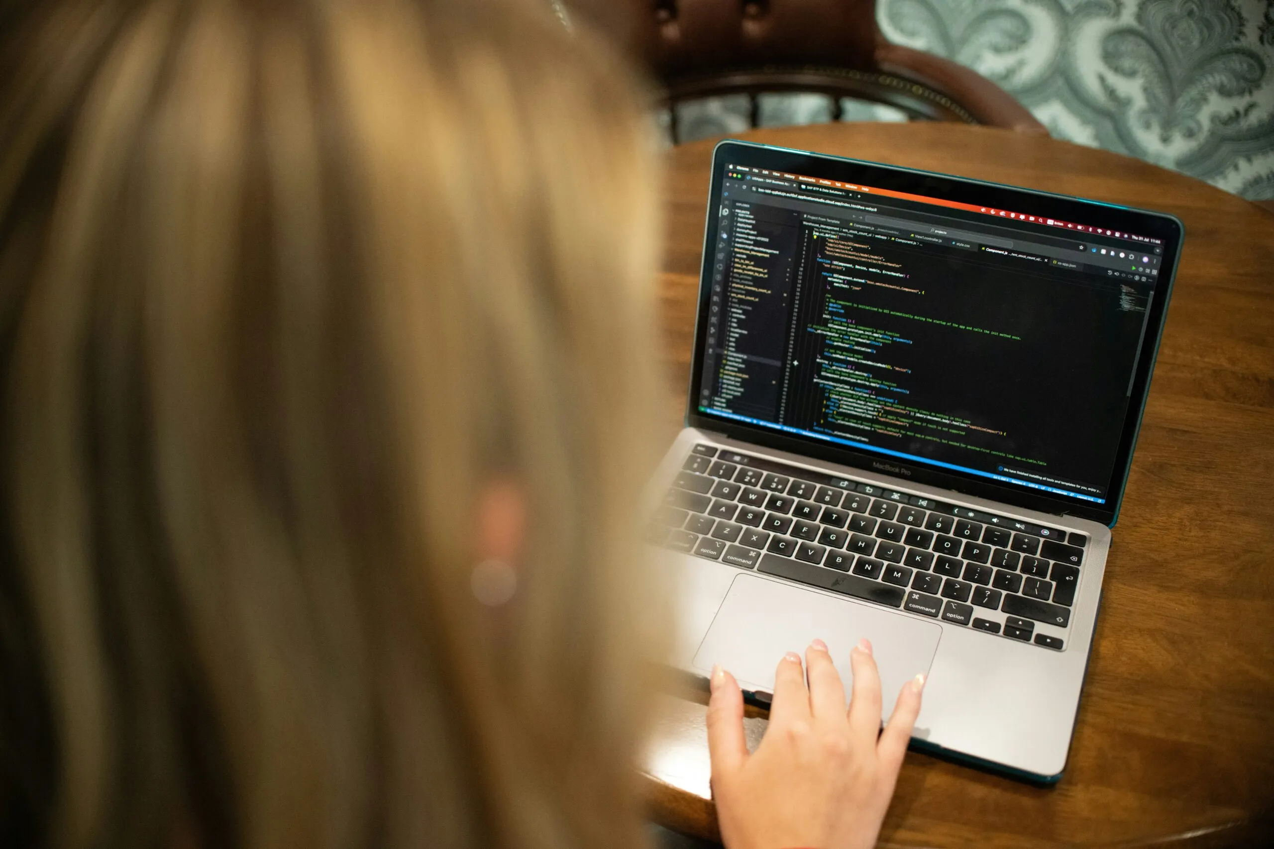 Woman typing code on a laptop computer.