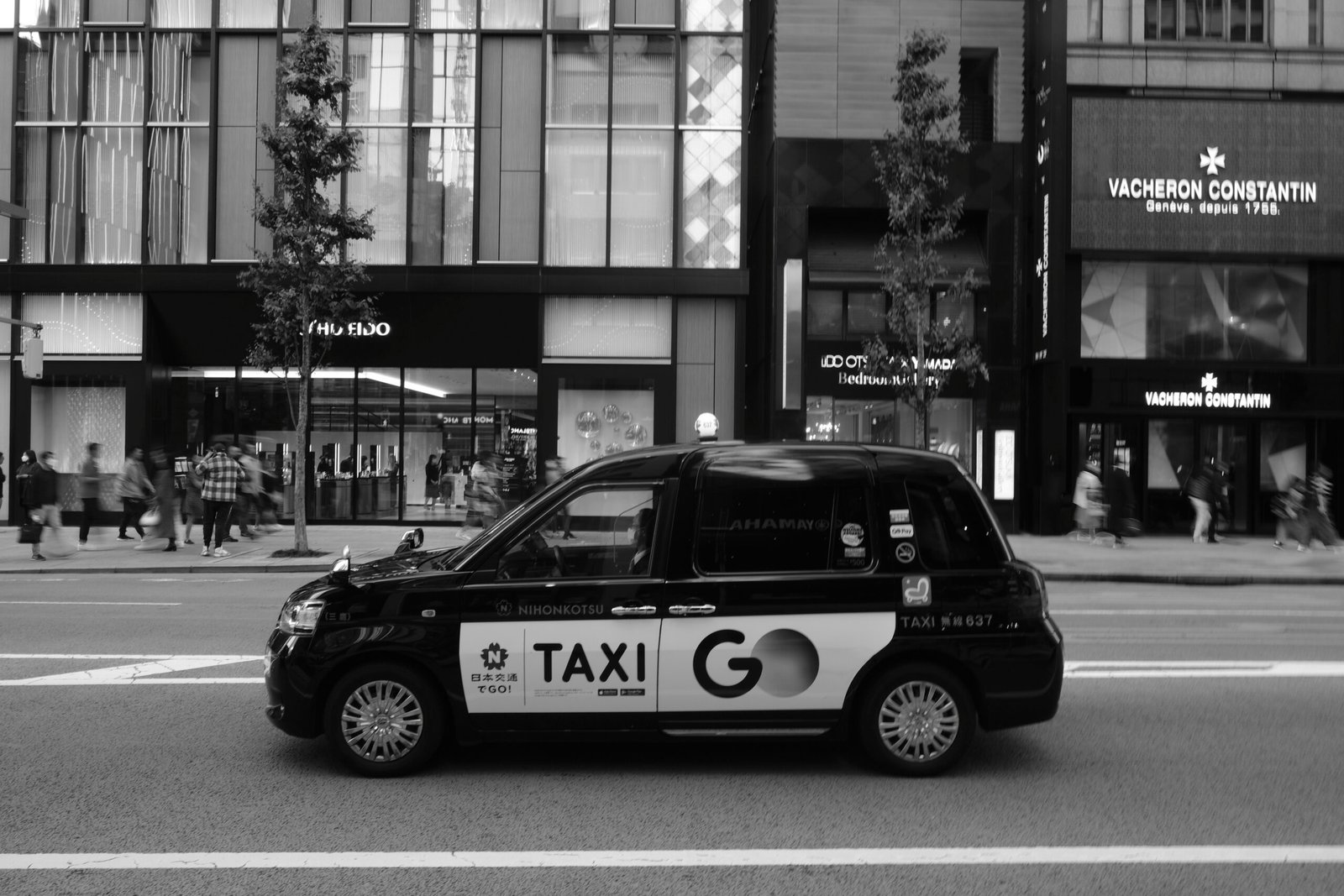 A taxi go drives down a city street.