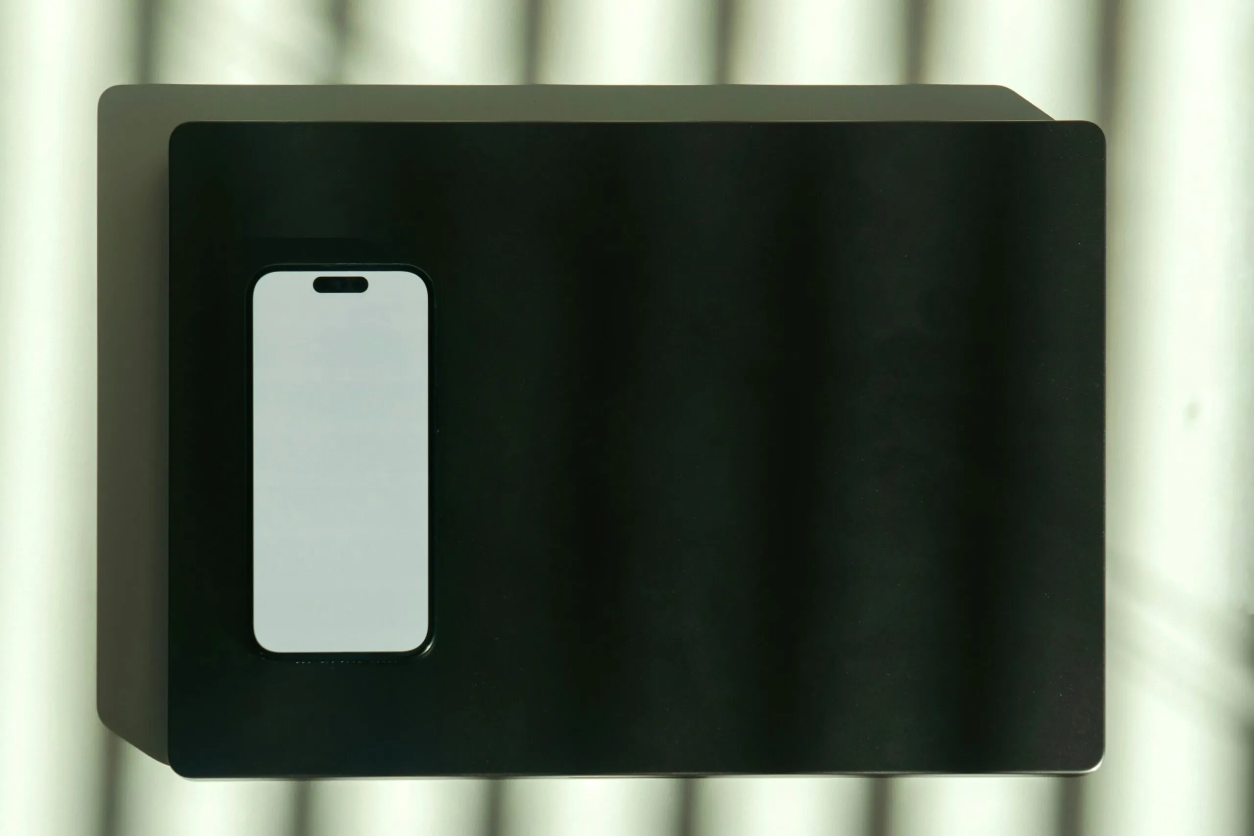 A white smartphone is placed on a black surface.