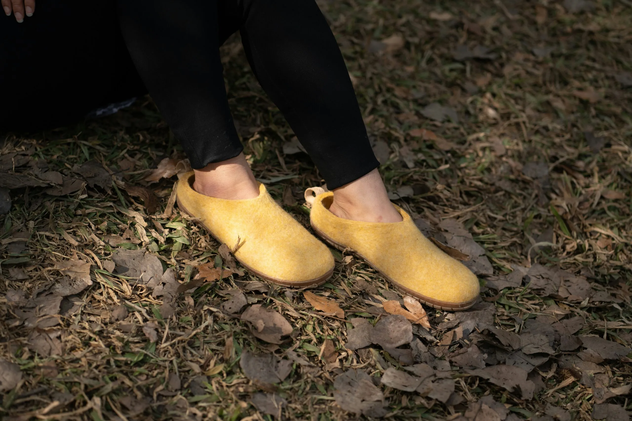 Person wearing yellow shoes in a grassy area.