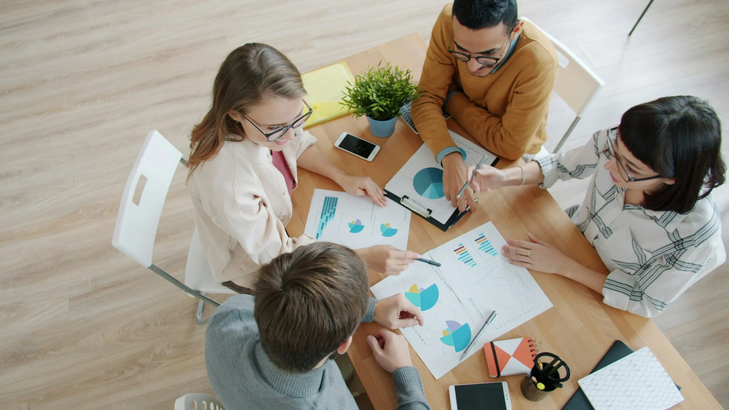 Four people collaborating around a table with charts.