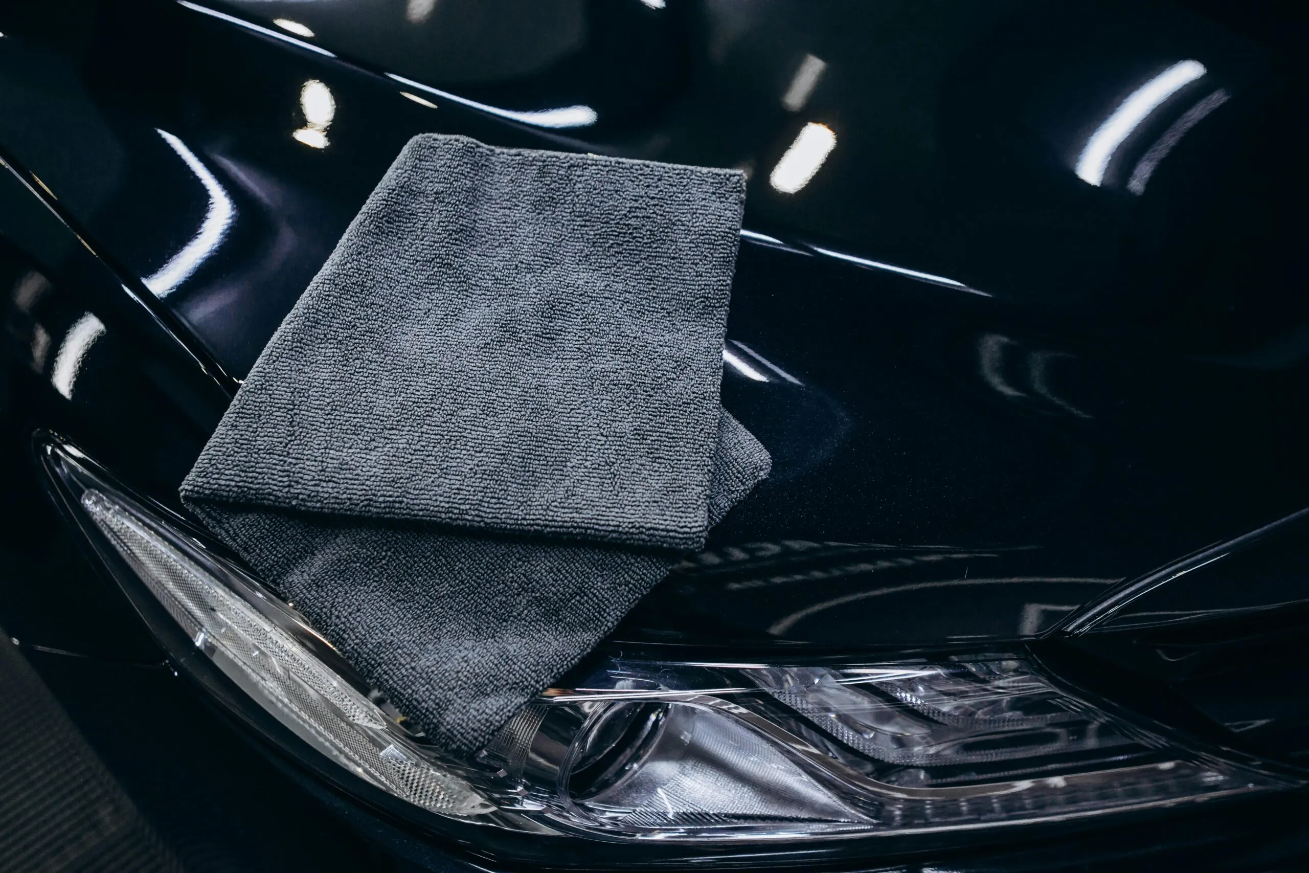 Gray microfiber cloth on a black car hood.