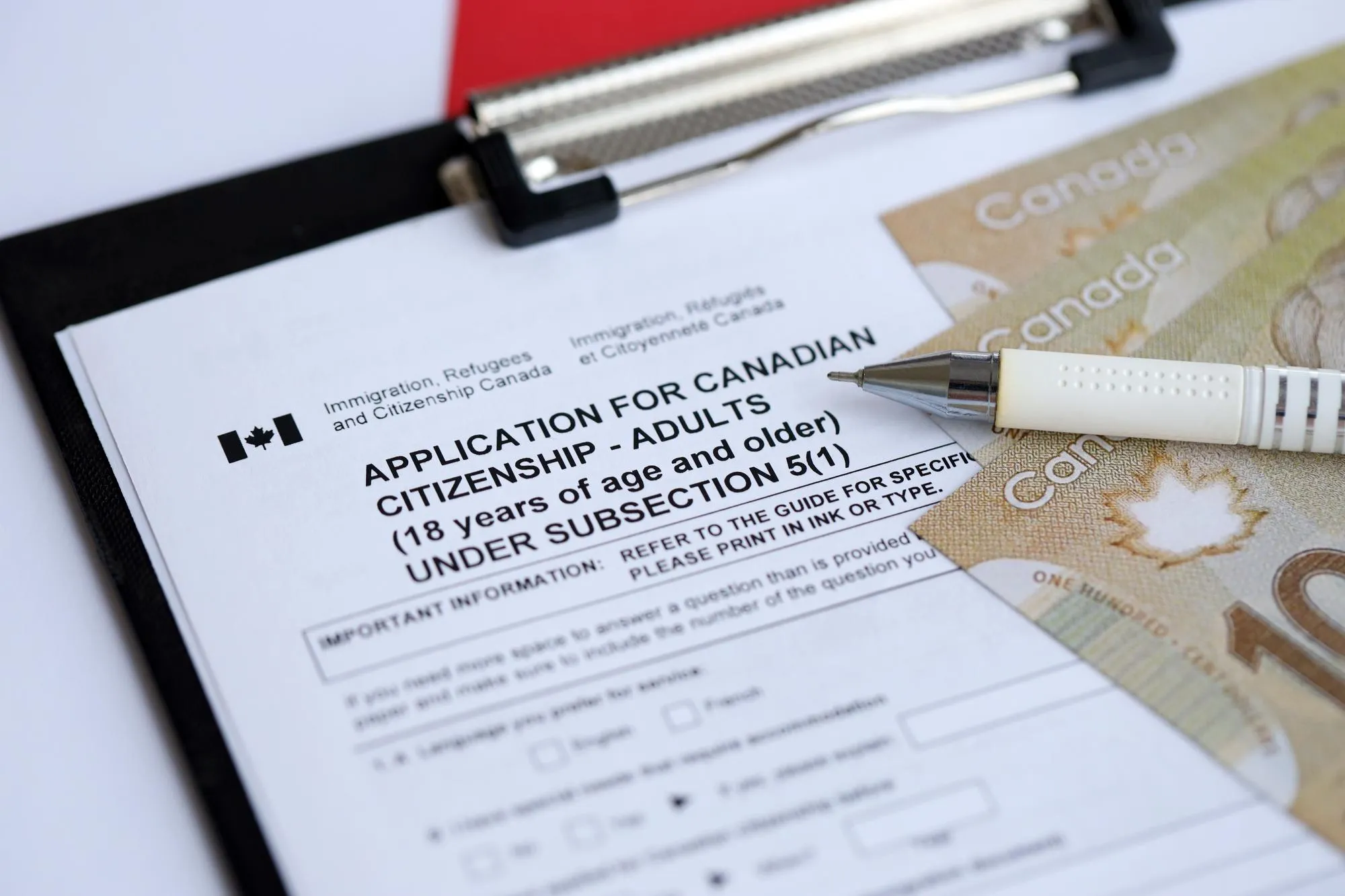 Application for canadian citizenship for adults on table with pen and dollar bills close up