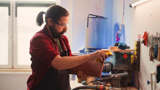 Artisan with safety glasses next to apprentice using sanding block
