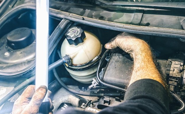 Auto mechanic working on car engine in a mechanics garage with a neon lamp. Repair service. authentic close-up shot