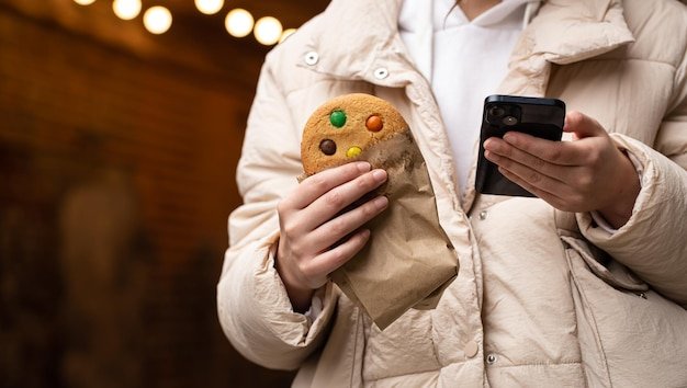 A beautiful gingerbread and a smartphone in the hands of a woman