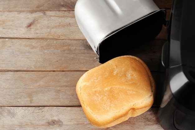 Bread machine with loaf on wooden table