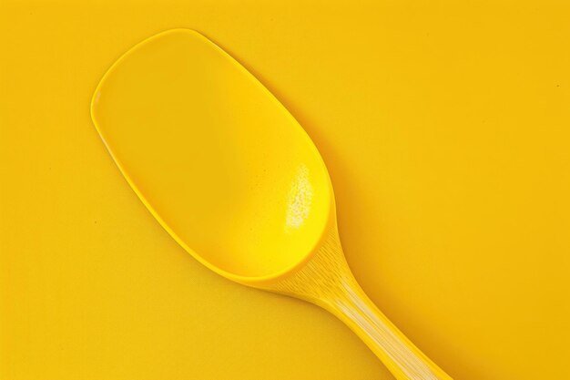 Bright yellow kitchen spatula resting on a vibrant yellow surface