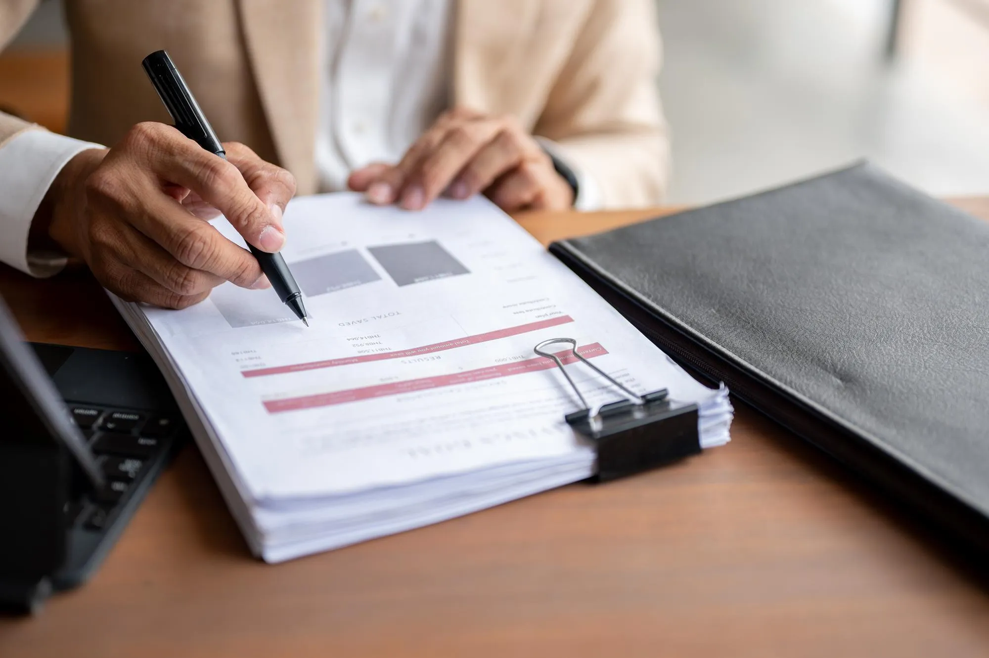 A businessman is reviewing business document at a table having a meeting with his team