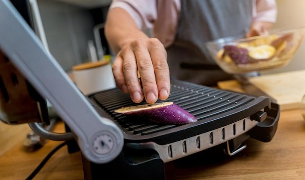 Chef at the kitchen preparing grilled eggplants with garlic