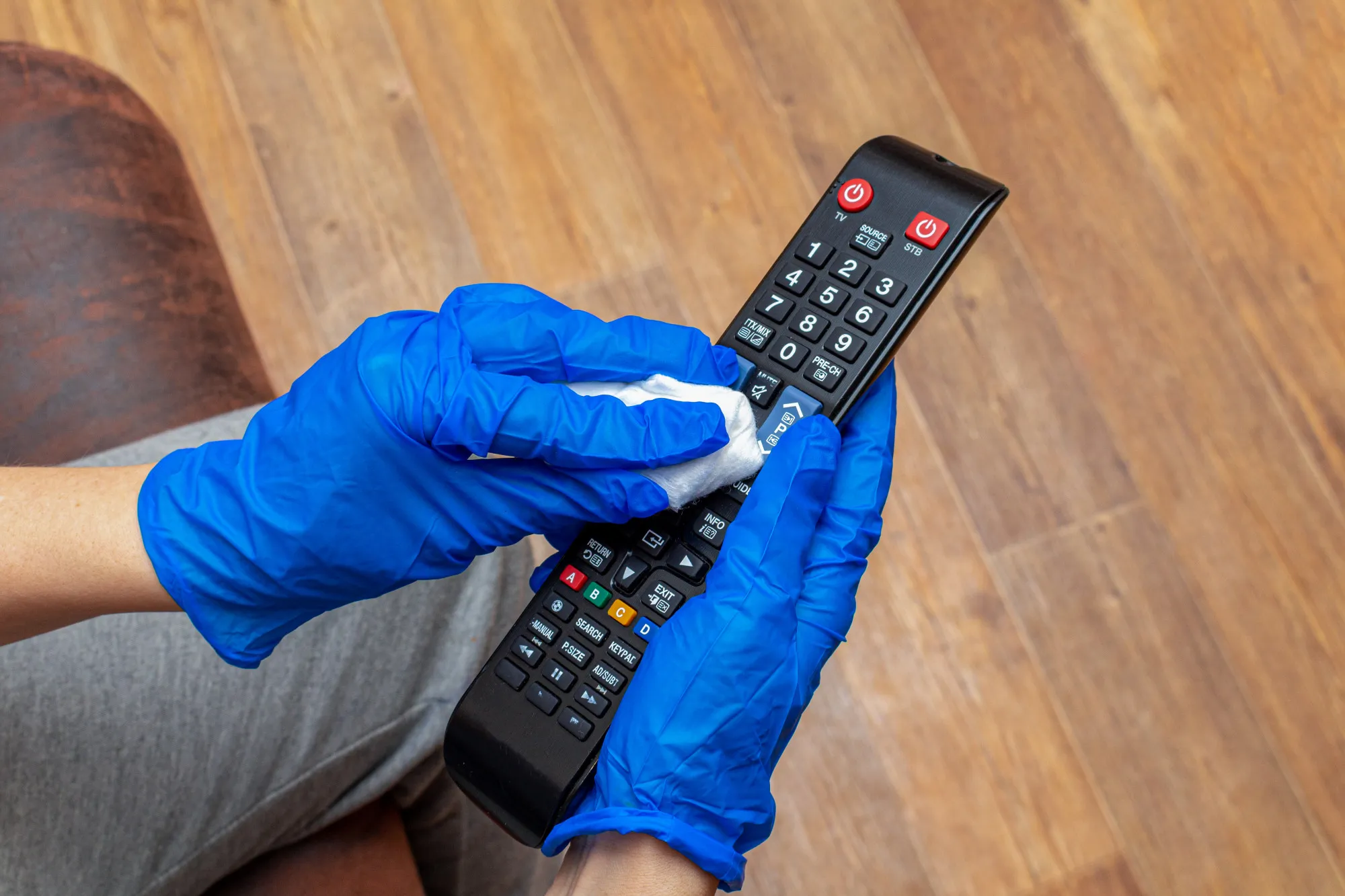 Cleaning, disinfecting, wiping remote control panel with a hand in glove and napkin