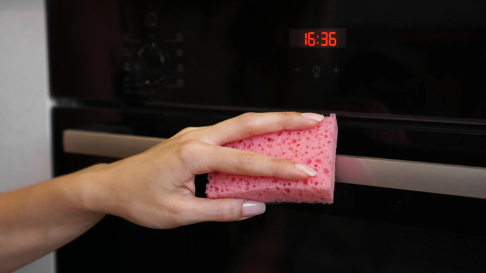Cleaning the oven outside. A female hand cleans oven panel. Girl polishing kitchen