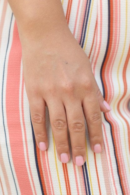 Closeup Hand with Pink Nail Polish on Striped Fabric