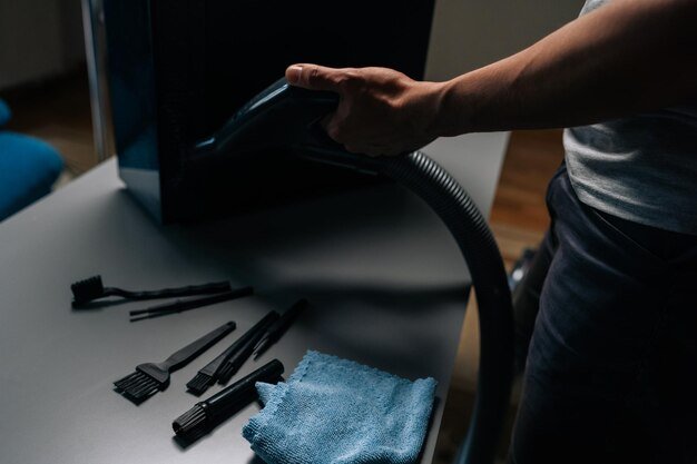 Computer technician cleaning computer case with vacuum cleaner different brushes and microfiber