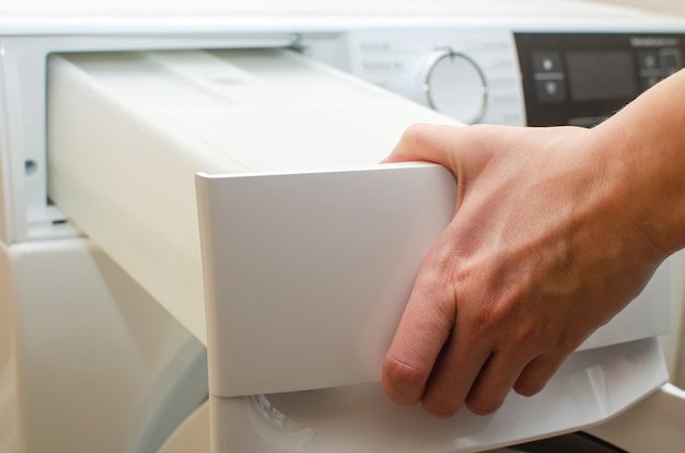 A container for condensate from the dryer, a woman takes out a tank with accumulated water after drying clothes from the dryer.