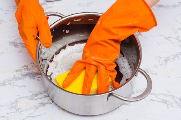 Female hands lather the pan with a sponge for washing dishes on the table
