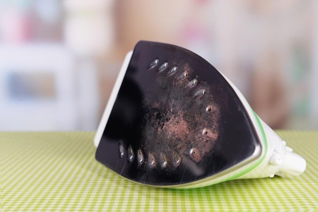 Flat iron with burnt mark on table on bright background