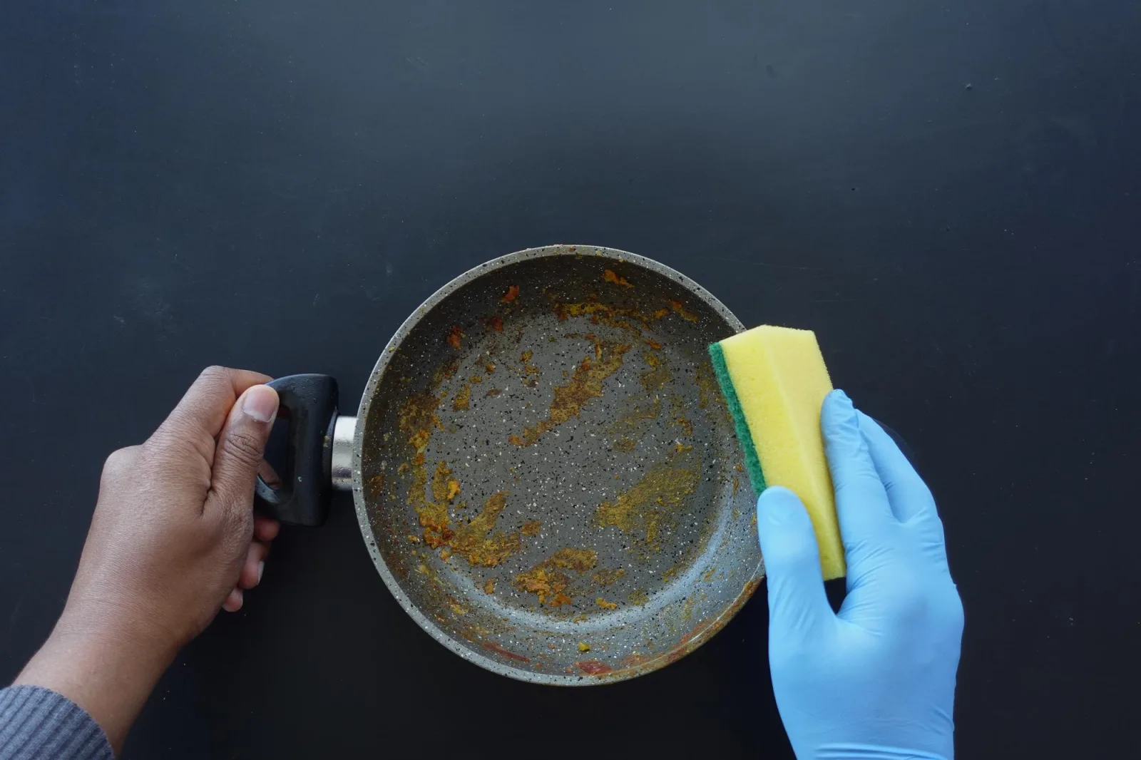 Hand with sponge cleaning dirty pan