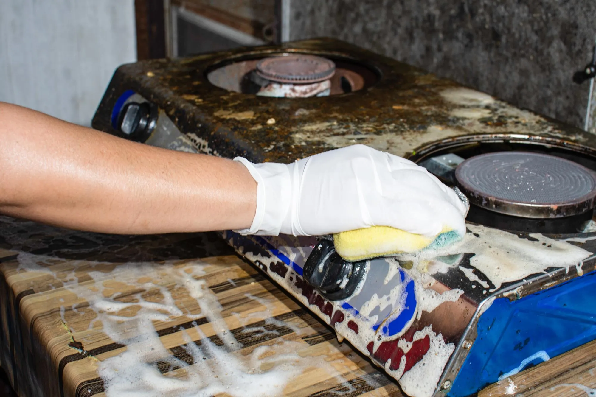 The housewife scrubbed the strains attached to the gas stove The gas stove has stubborn stains must be rubbed with foam solutionxAThe woman is cleaning the dirty gas stove with a stain remover