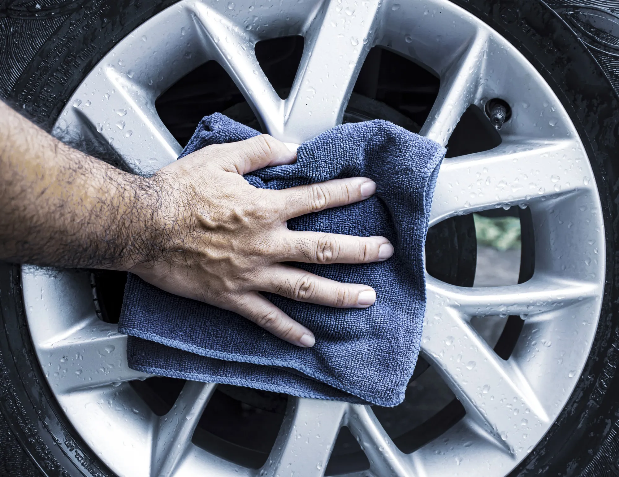 Human hand is wipe the alloy wheel of the car with a microfiber cloth