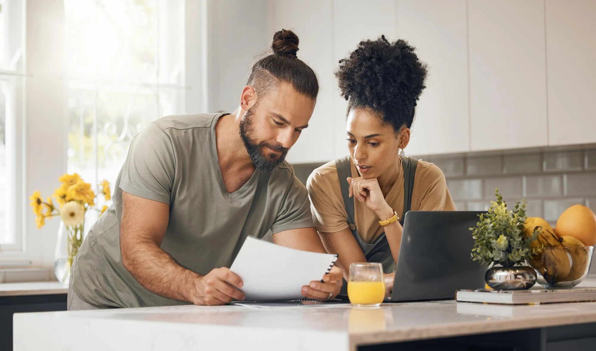 Interracial couple laptop in kitchen and insurance paperwork budget and finance with life and marriage Partner people at home and reading document with policy taxes and bills with mortgage