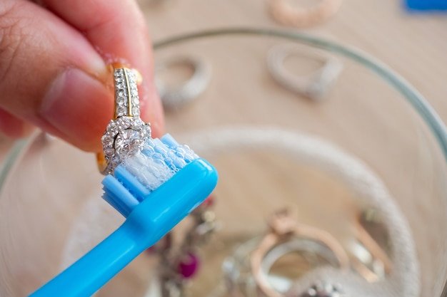Jeweller hand cleaning and polishing vintage jewelry diamond ring closeup