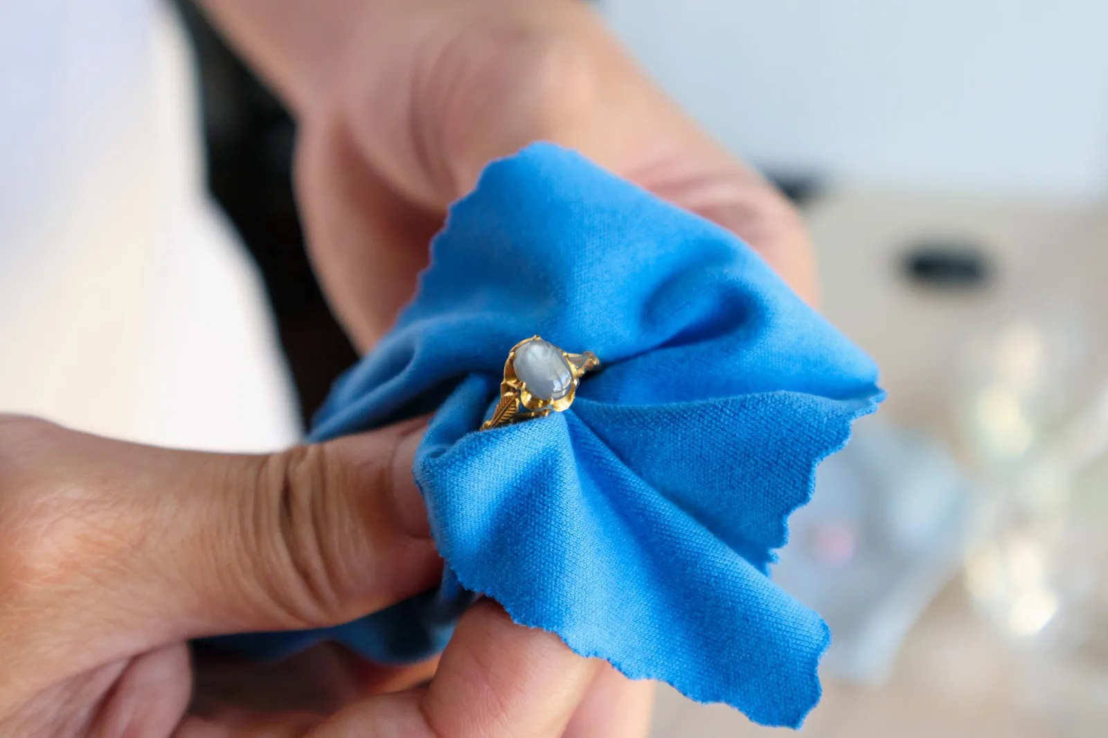 Jeweller hand polishing and cleaning gold jewelry ring with micro fiber fabric