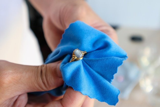 Jeweller hand polishing and cleaning gold jewelry ring with micro fiber fabric