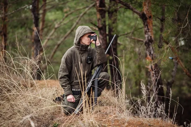 Male hunter with binoculars ready to hunt holding gun and walking in forest