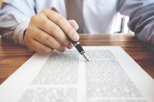 Midsection of businessman holding pen on paper