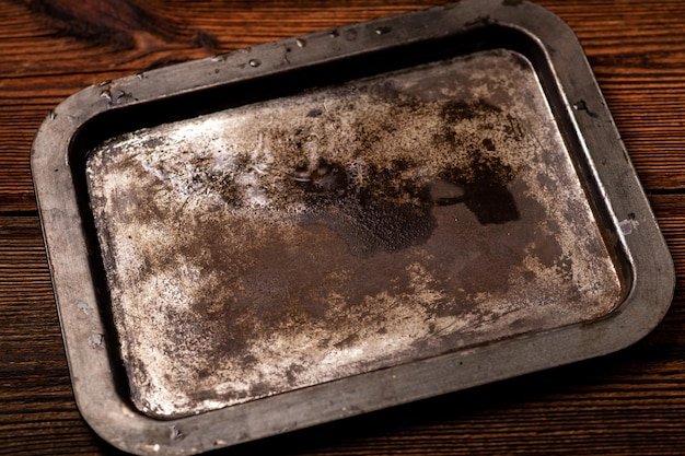 Old rusty steel tray on a dark wooden background Place for text