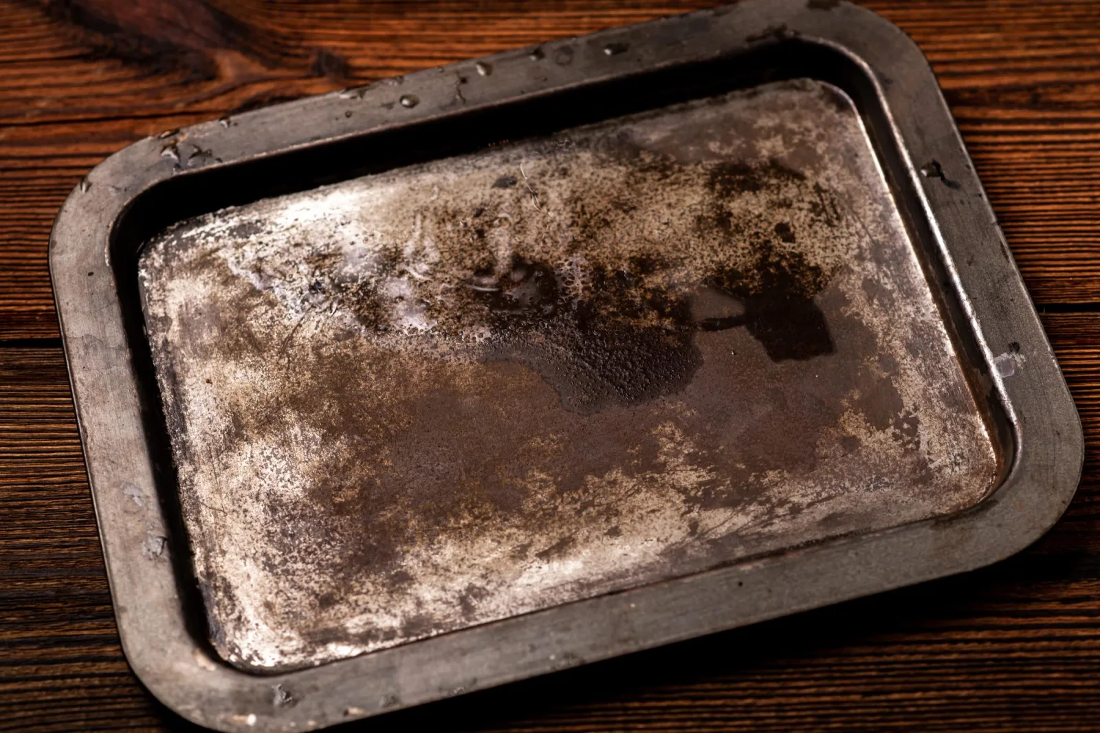 Old rusty steel tray on a dark wooden background Place for text