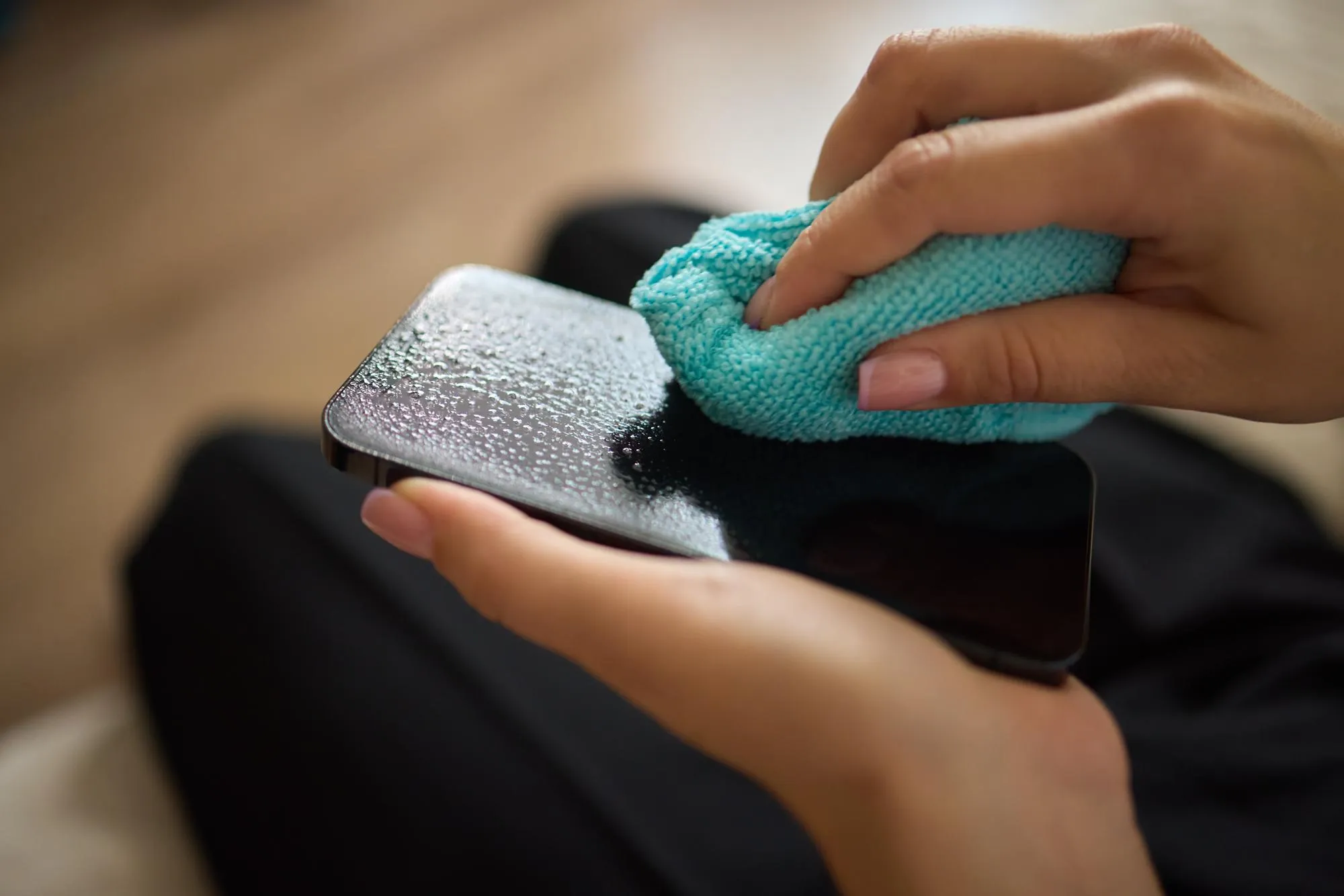 A person is using a microfiber cloth to clean their smartphone for hygiene purposes