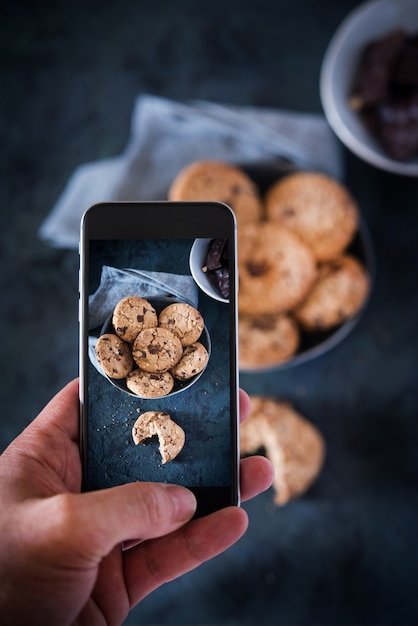 Person taking picture with a phone to some cookies with chocolate