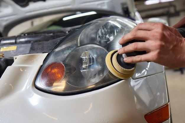 Person using a machine to polish automotive lighting on a car headlight
