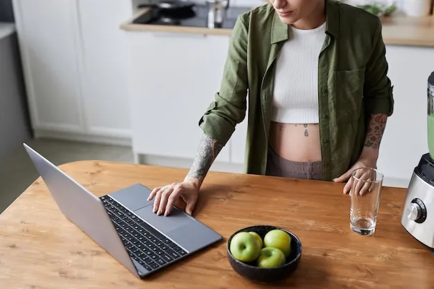 Pregnant young woman using laptop in kitchen interior checking work messages