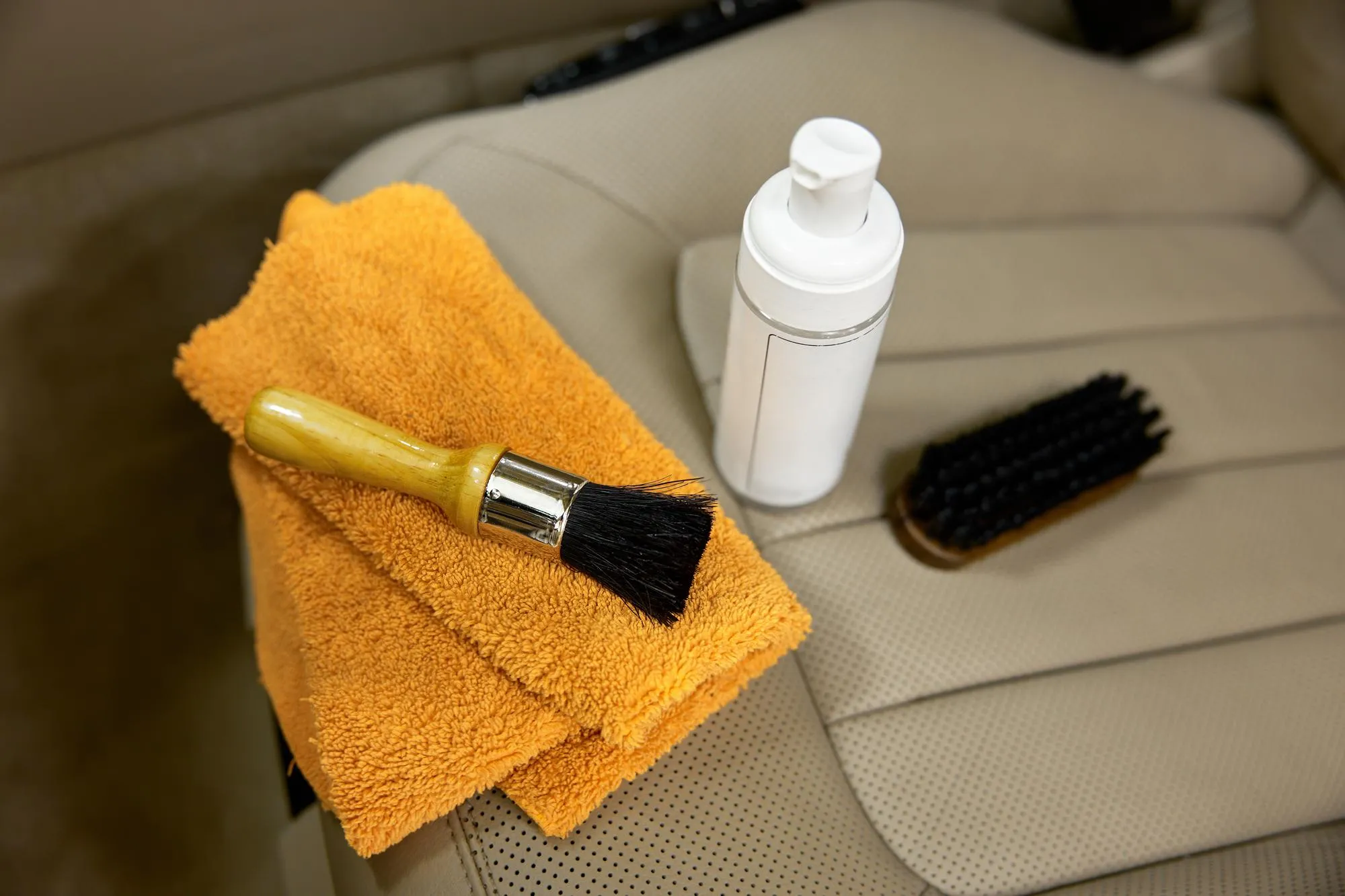 Professional tools and cosmetics of premium quality for car detailing and cleaning service. Foam detergent, different type of soft brush and rag over auto leather interior design