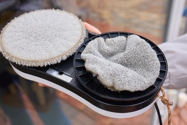 A robotic white Automotive tire is cleaning a glass window replacing cleaning cloths