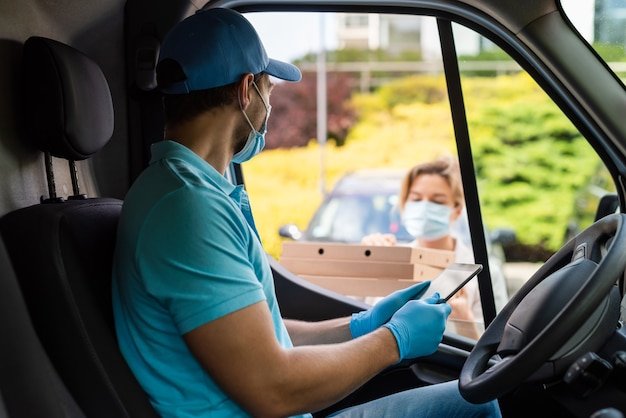 Safe delivery - courier on a van brings a pizza to the client