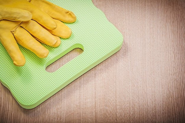 Safety leather gloves garden foam kneeling pad on wooden board gardening concept