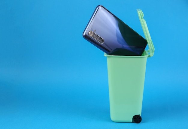 Smartphone in trash can on pink background Pollution recycling concept