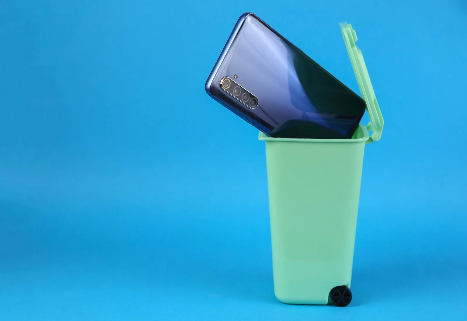 Smartphone in trash can on pink background Pollution recycling concept